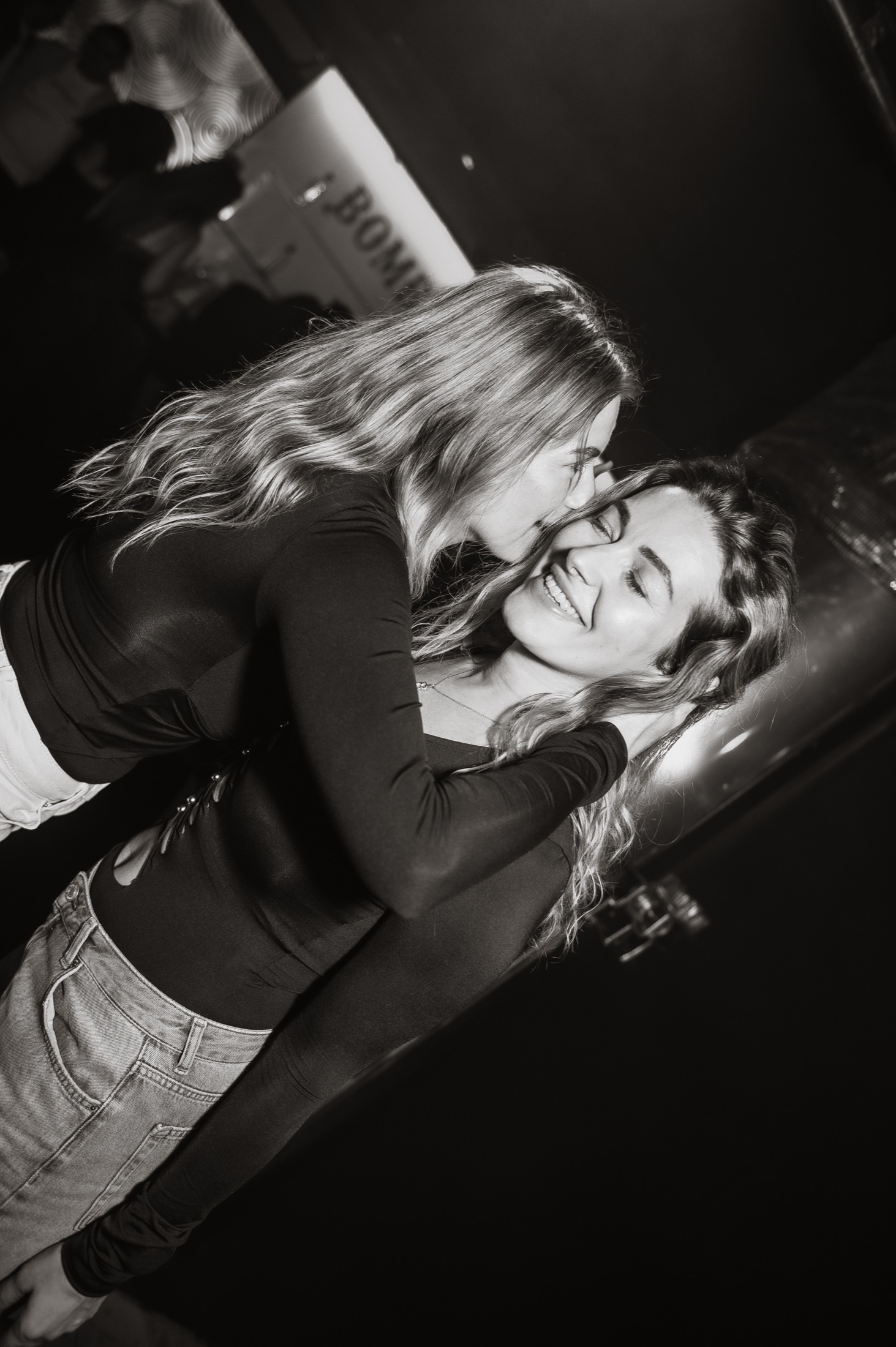 Two friends embracing on the dance floor, photographed in black and white