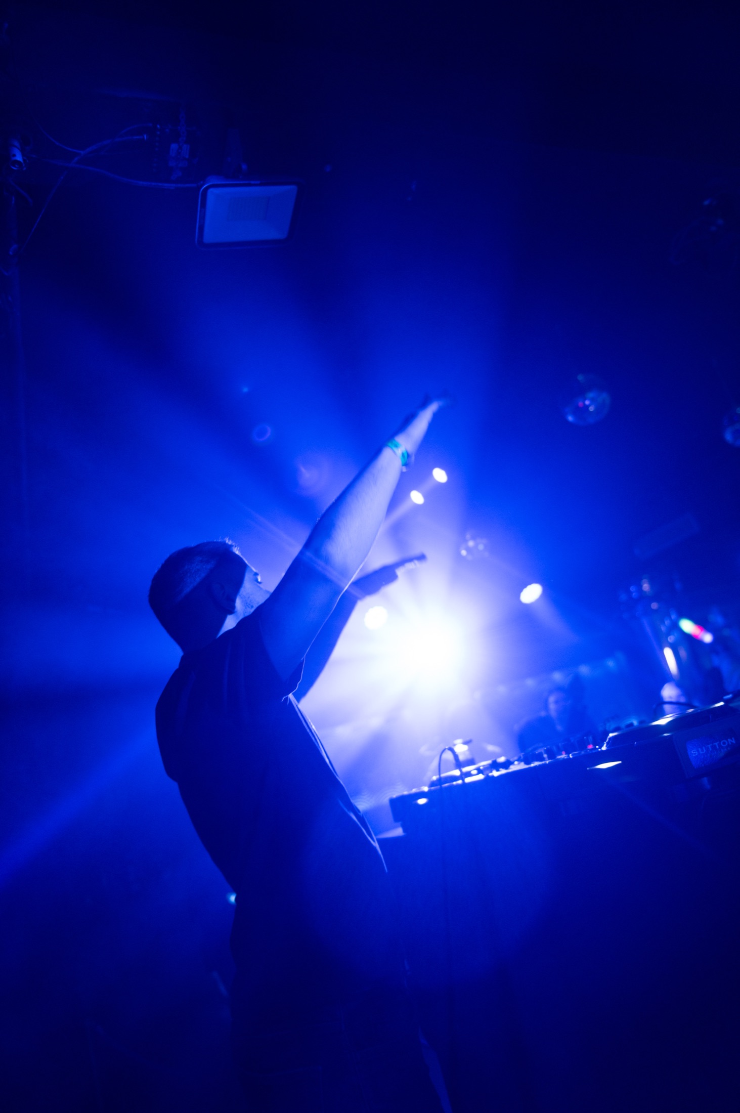 DJ raising one hand into intense blue stage light